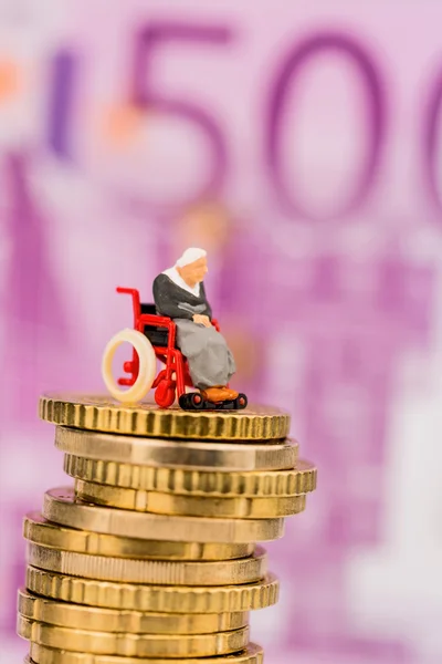 Frau im Rollstuhl auf Geldstapel — Stockfoto