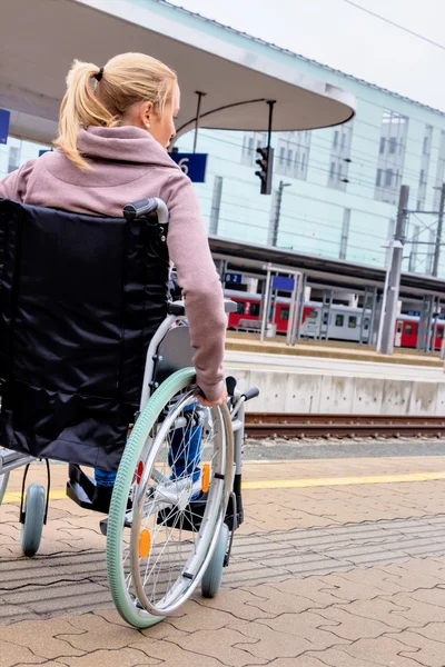 Kobieta siedzi na wózku inwalidzkim na stacji kolejowej — Zdjęcie stockowe