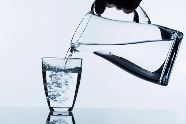 Glass with water and jug — Stock Photo, Image