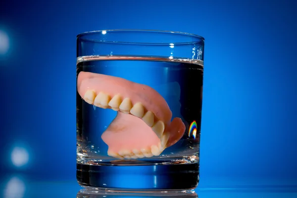 Dentures in water glass — Stock Photo, Image