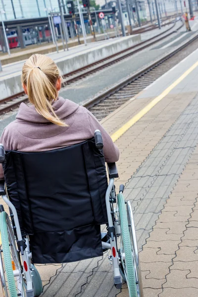 Bir tren istasyonunda bir tekerlekli sandalyede oturan kadın — Stok fotoğraf