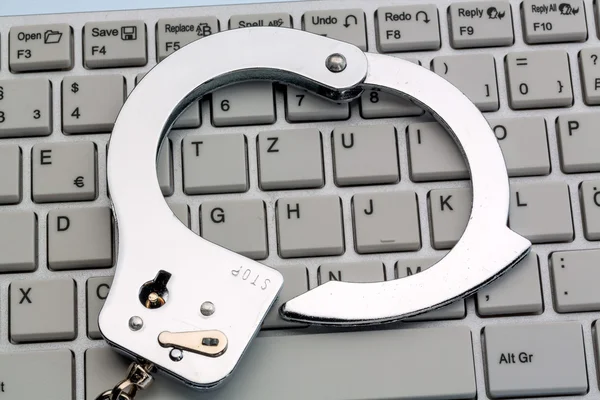 Handcuffs on computer keyboard — Stock Photo, Image