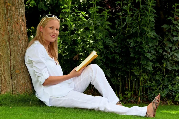 Kvinna läser bok i parken — Stockfoto