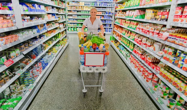 Mulher com carrinho de compras no supermercado — Fotografia de Stock