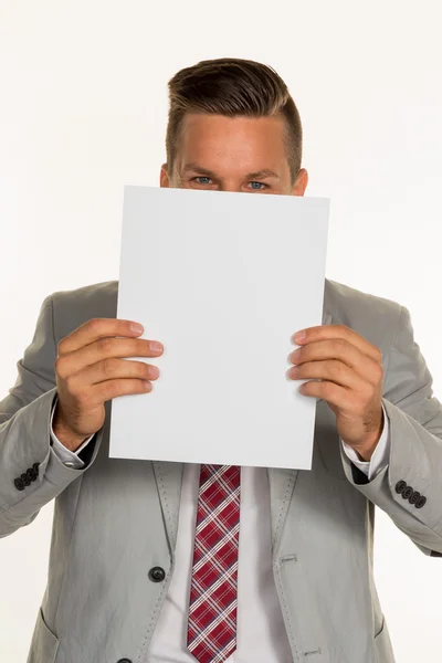 Manager holding blank sheet in front of face — Stock Photo, Image