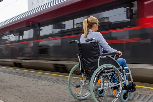 Donna seduta su una sedia a rotelle in una stazione ferroviaria — Foto Stock