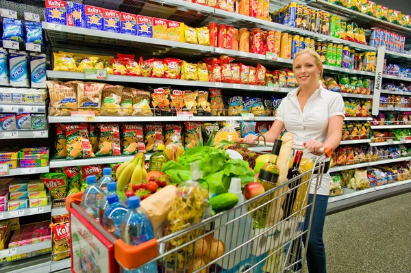 Woman with shopping cart in the supermarket — Stock Photo, Image