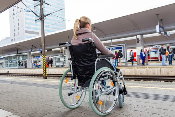 Donna seduta su una sedia a rotelle in una stazione ferroviaria — Foto Stock