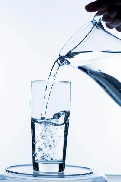 Glass with water and jug — Stock Photo, Image