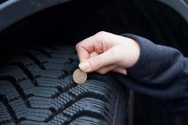 Vrouw maatregelen tire tread van een auto band — Stockfoto