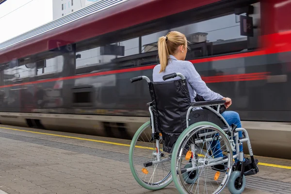 Femme assise dans un fauteuil roulant dans une gare — Photo