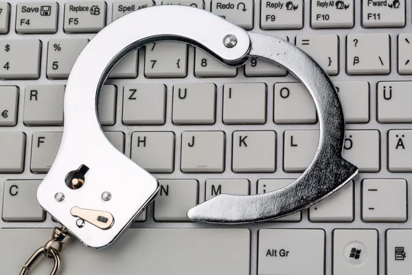 Handcuffs on computer keyboard — Stock Photo, Image
