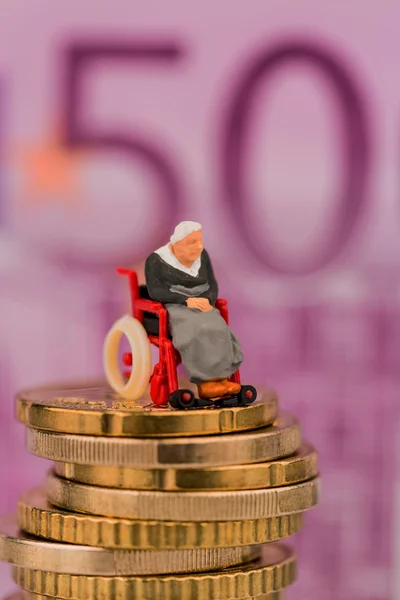 Woman in wheelchair on geldstapel — Stock Photo, Image