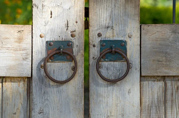 Portão de madeira com ferrugem velhos batedores de ferro — Fotografia de Stock