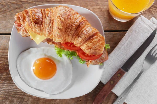 Croissant sandwich con pancetta fritta pomodoro colazione e uova — Foto Stock