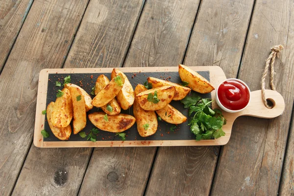 Baked roasted potato wedges with herbs and red sauce — Stock Photo, Image