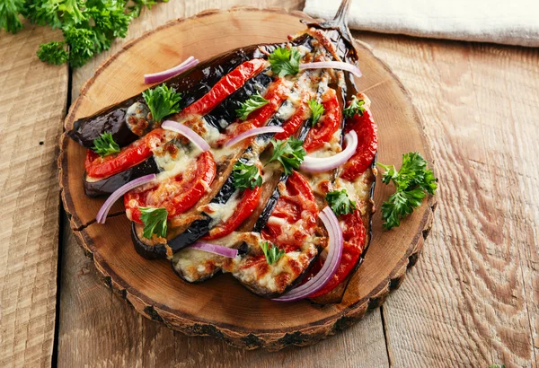 Baked eggplant with cheese and tomatoes on a wooden surface — Stock Photo, Image