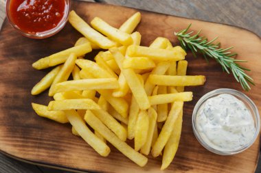 Bir kesme tahtası üzerinde soslu patates kızartması