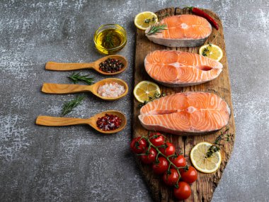 Tahta tahtada üç çiğ balık, somon ve baharat, koyu arka plan.