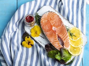 Çiğ taze balık alabalığı, somon ve baharatlar mavi ahşap arka planda.