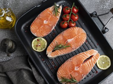 Üç çiğ balık balığı, somon balığı ve ızgara tavasında baharat, koyu arka plan, yukarıdan manzara.