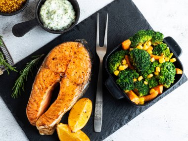 Rosto, fırında balık bifteği somon, brokoli ve havuçlu alabalık, taş yüzeyde, üst manzara.