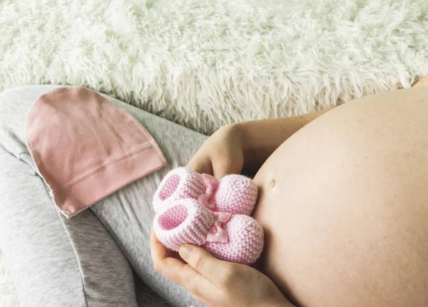 Nahaufnahme Einer Schwangeren Frau Mit Gestrickten Rosafarbenen Babybooties Auf Dem — Stockfoto