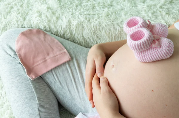 Nahaufnahme Einer Schwangeren Frau Mit Gestrickten Rosafarbenen Babybooties Auf Dem — Stockfoto