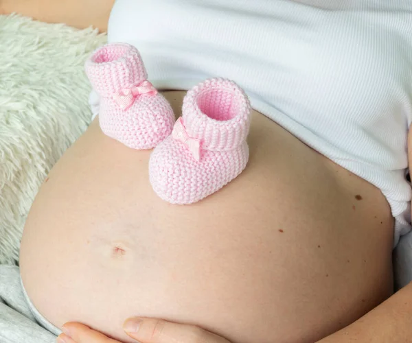 Nahaufnahme Einer Schwangeren Frau Mit Gestrickten Rosafarbenen Babybooties Auf Dem — Stockfoto