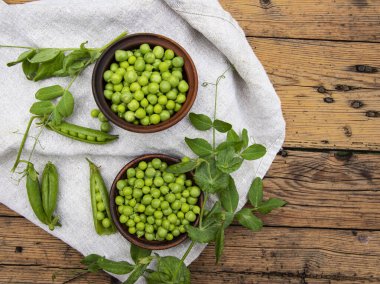 Seramik kasede taze bezelyeler, kapsüller, masanın üstünde, üst manzara, tohumlar.
