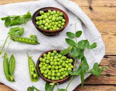Seramik kasede taze bezelyeler, kabuklar, eski ahşap bir yüzey üzerinde.