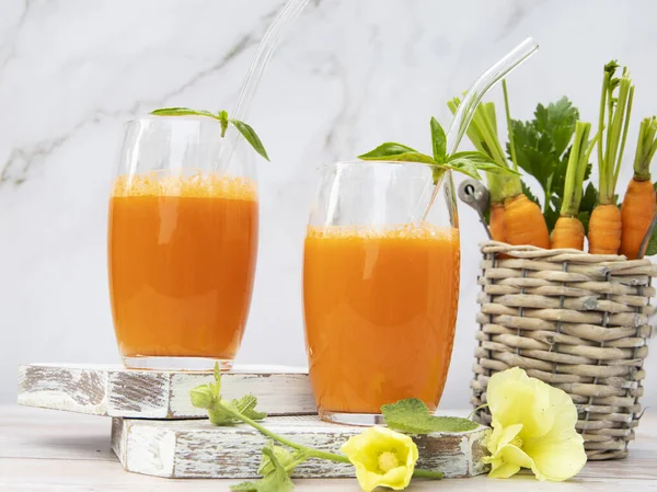 在木制表面的玻璃杯中加入新鲜的榨胡萝卜汁 乡村音乐风格健康饮食 节食和素食理念 图库图片