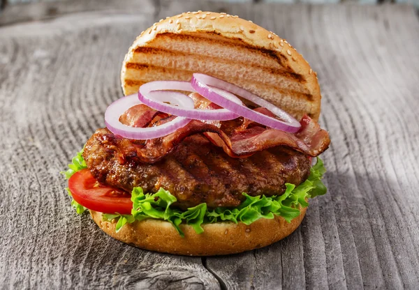 Hamburger, szalonnával és grillezett hús egy fa felületre — Stock Fotó