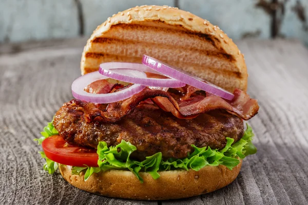 Hamburger, szalonnával és grillezett hús egy fa felületre — Stock Fotó