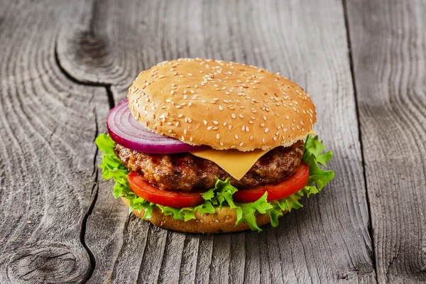 Hamburger con carne alla griglia e formaggio su una superficie di legno — Foto Stock