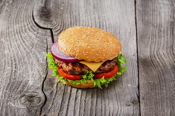 Hamburger with grilled meat and cheese on a wooden surface — Stock Photo, Image