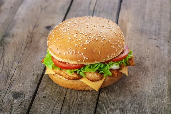 Hambúrguer com frango e queijo em uma superfície de madeira — Fotografia de Stock