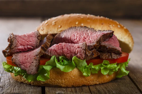 Sandwich de hamburguesa asada sobre una superficie de madera — Foto de Stock