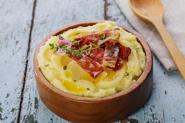 Mashed potatoes with bacon in a wooden bowl — Stock Photo, Image