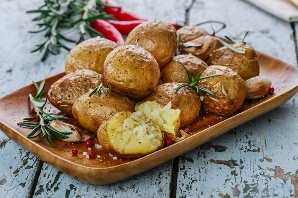 Batatas assadas inteiras em suas peles com alecrim e alho — Fotografia de Stock