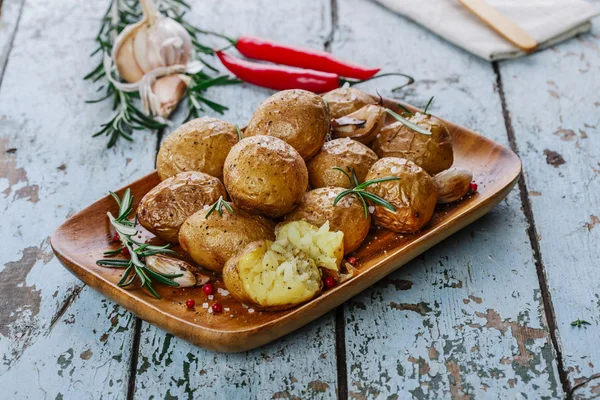 Batatas assadas inteiras em suas peles com alecrim e alho — Fotografia de Stock