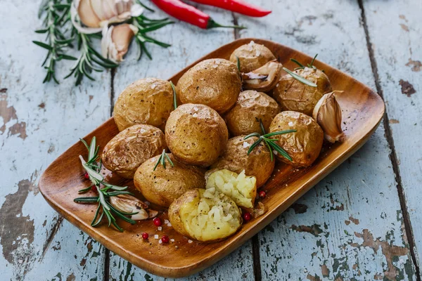 Batatas assadas inteiras em suas peles com alecrim e alho — Fotografia de Stock