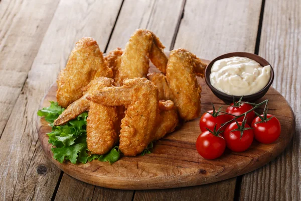 Gebakken Kippenvleugels met saus en tomaten — Stockfoto