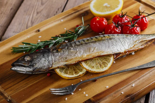 Baked mackerel with tomato and lemon on wooden board — Stock Photo, Image