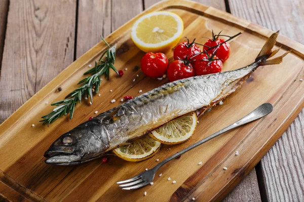 Baked mackerel with tomato and lemon on wooden board — Stock Photo, Image