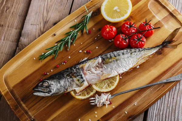 Baked mackerel with tomato and lemon on wooden board — Stock Photo, Image