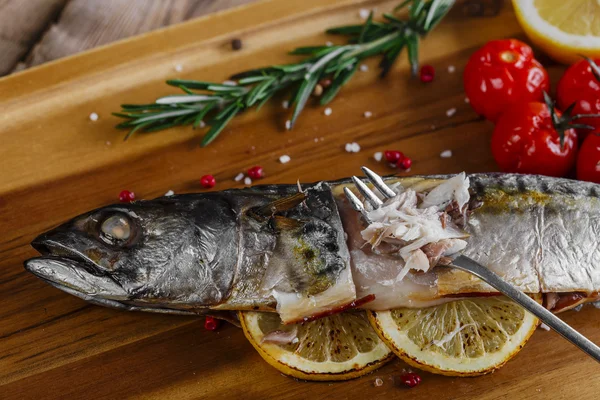 Baked mackerel with tomato and lemon on wooden board — Stock Photo, Image