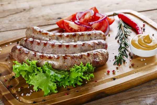 Grilled sausages on the grill on the board — Stock Photo, Image