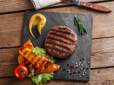 Hamburger ızgara sebzeler ve sos bir ahşap yüzeye