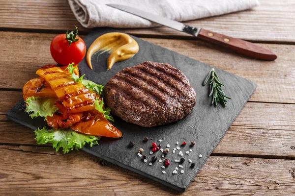 Griglia di hamburger con verdure e salsa su una superficie di legno — Foto Stock